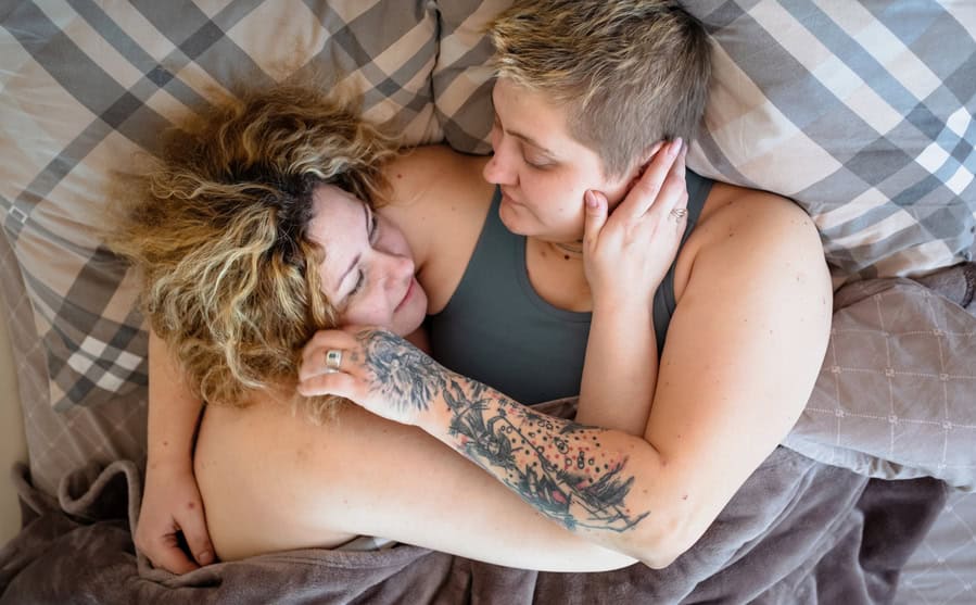 Lgbt female couple joy of life lying in bed hugging